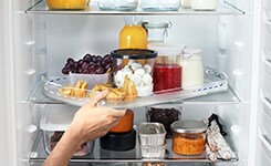 Hand taking out tray from fridge